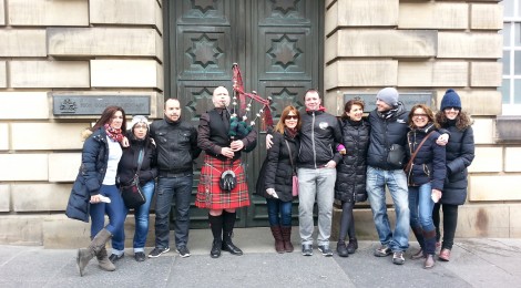 Turistas junto a un gaitero en la Royal Mile de Edimburgo durante un tour de Edina Tours